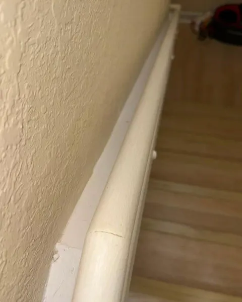 After: white stair handrail above wooden steps after cleaning.
