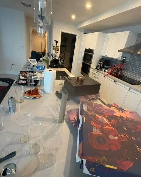 Before: kitchen island covered with used glasses, food containers, paper towels and bags.