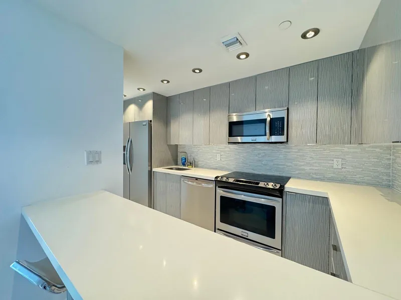 Kitchen with light countertops, gray cabinets and stainless steel appliances.