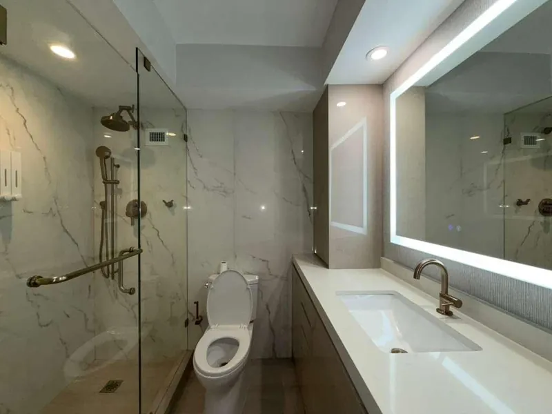 Bathroom with a glass shower, white vanity countertop and illuminated mirror.